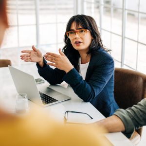 Professional woman talking to her team in an office meeting. Young business woman having a discussion with her colleagues. Group of business professionals brainstorming in an office.